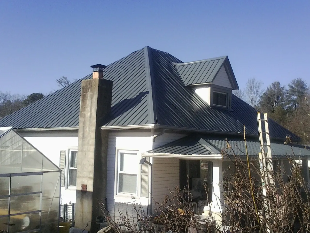 Dark blue standing seam metal roof on a white farmhouse with dormer — Slate & Tile Roof Repair by Roofing Brothers in Gurnee