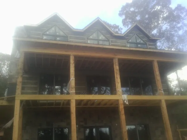 Dormers and porch framing on a large log home under construction — Roof Coating work by our crew in Gurnee