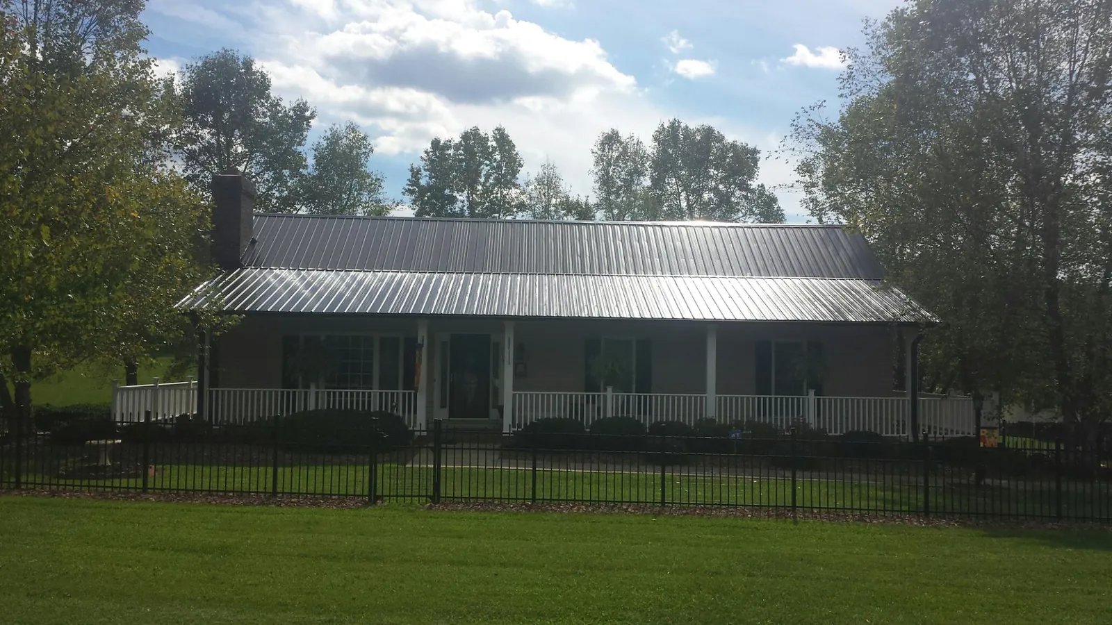 Gray metal roof on a brick ranch with a full width front porch — Gutter Guard Installation work by our crew in Gurnee