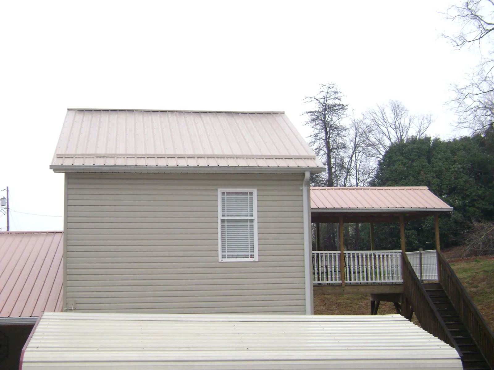 Tan metal roofs on a two story addition and attached porch, from a Roof Replacement job in Gurnee