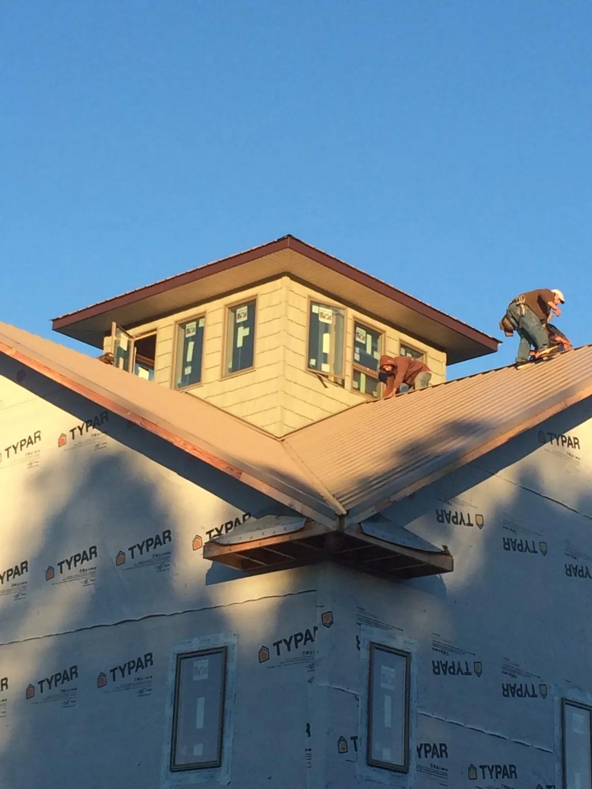 Roofers working around a rooftop cupola on a new metal roof at sunset — Roof Waterproofing in Gurnee by Roofing Brothers